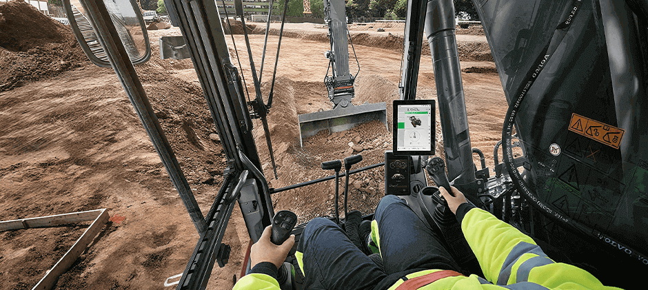 A person operates the equipment in the cab of an excavator