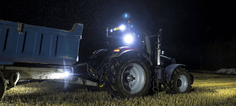 A person was working at night in a tractor with the lights on.