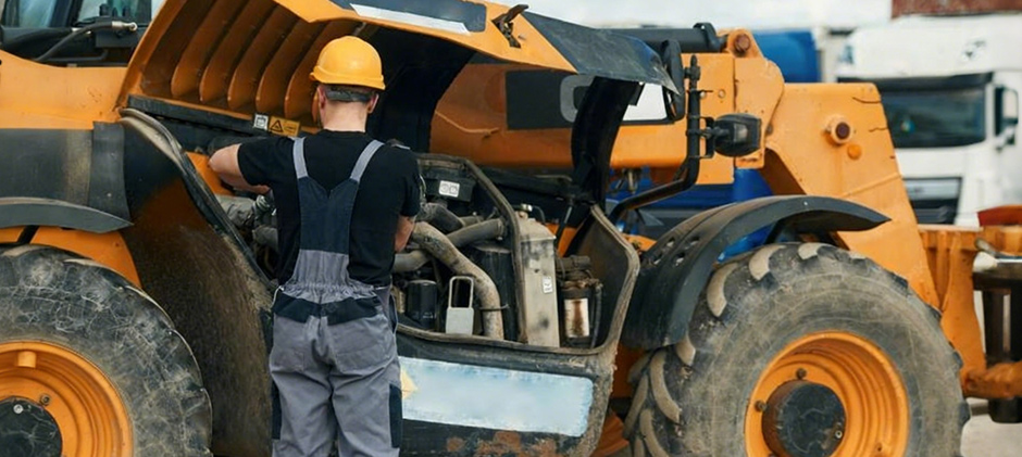 One person is inspecting the backhoe machine