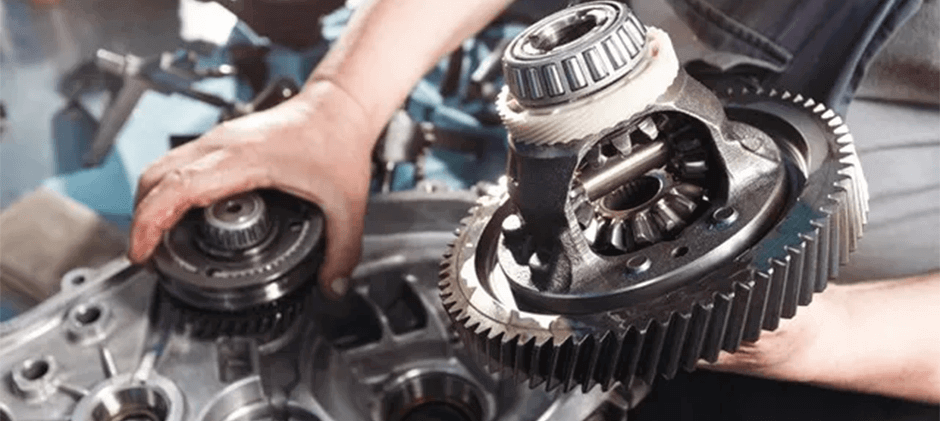 A mechanic's hands repairing the internal gears of a drivetrain, a common result of ignoring serious transfer case symptoms.