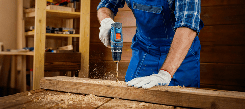 A cordless drill driver creating a clean hole in a wooden plank, demonstrating its core function of precise drilling.
