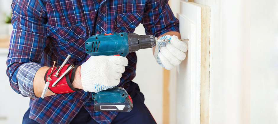 A worker using a cordless impact driver to efficiently drive a screw into a wooden frame.