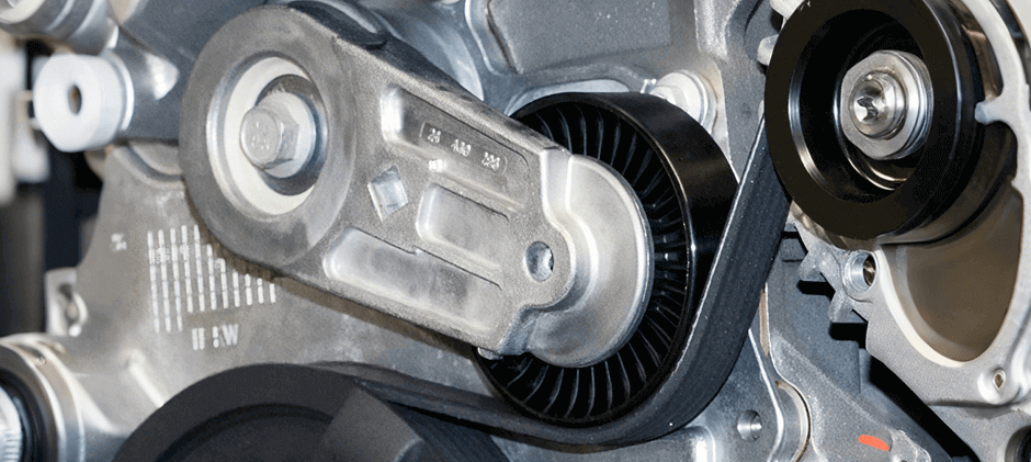 A close-up view of a new belt tensioner assembly on an engine, showing how it applies pressure to the serpentine belt.