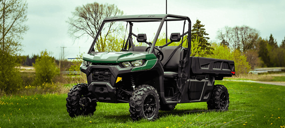  A Can-Am Defender PRO UTV parked in a field, showcasing its long cargo bed designed for hauling tools and materials.
