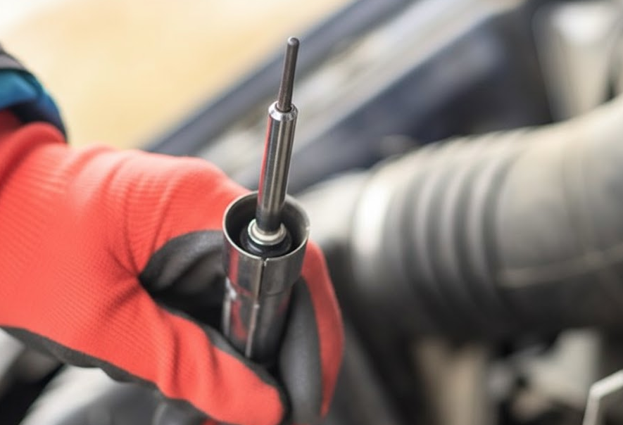 Mechanic holding a diesel glow plug during inspection