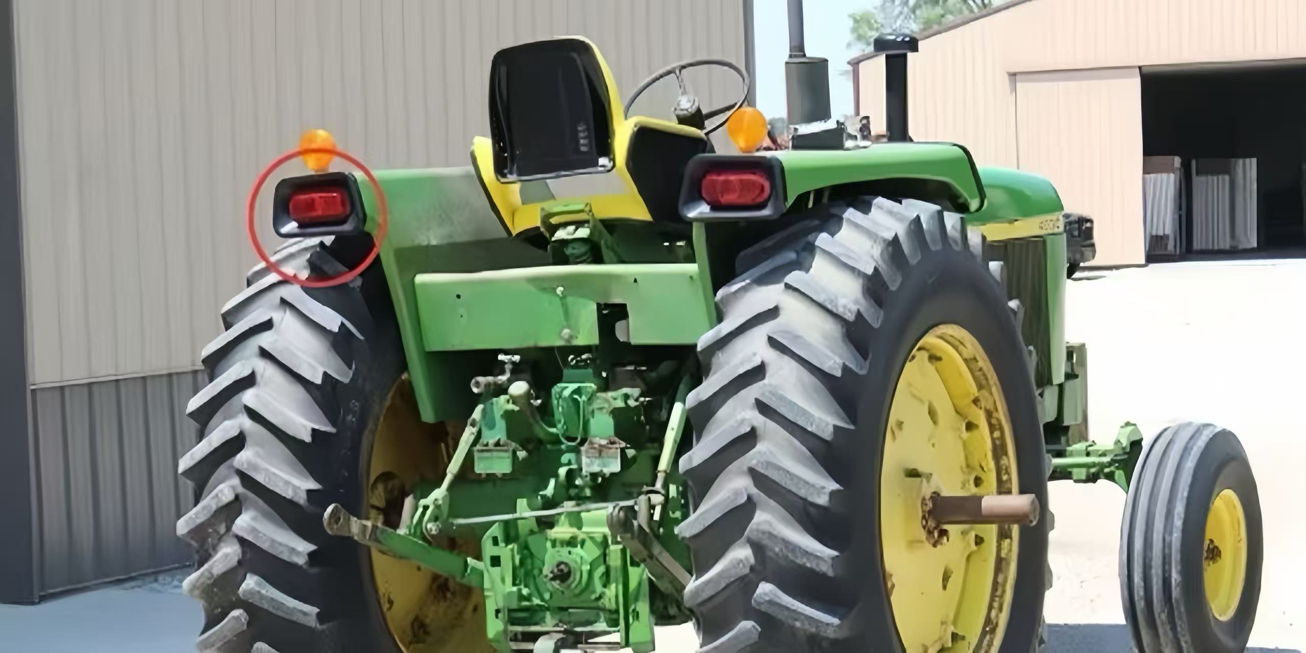 Rear view of a green tractor with the tail light circled in red.