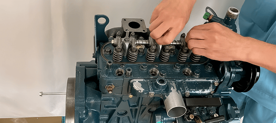 A mechanic's hands carefully adjusting the rocker arm assembly on top of a Kubota D1105 diesel engine during maintenance or an overhaul.