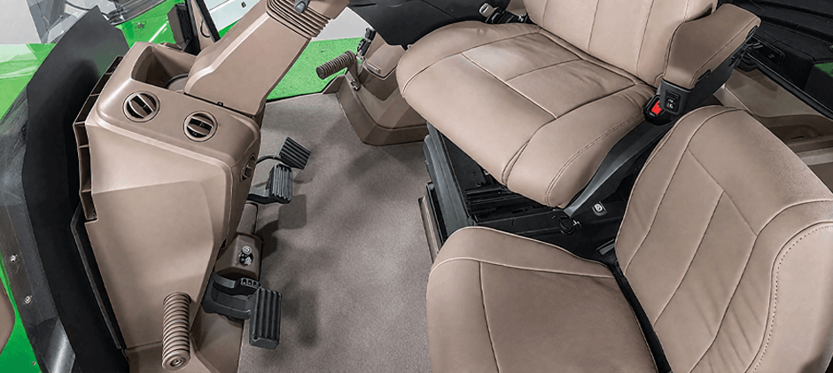 The spacious and modern interior of a heavy machinery cab, showing the operator's seat, controls, and a clear view of the floor pedals.