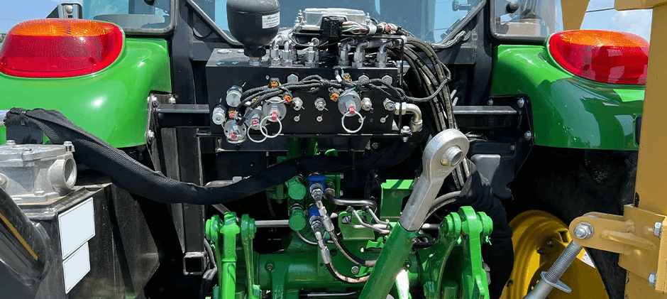 Rear view of a tractor's hydraulic system, showing multiple rear remote valves and Pioneer-style quick-disconnect couplers for powering implements.