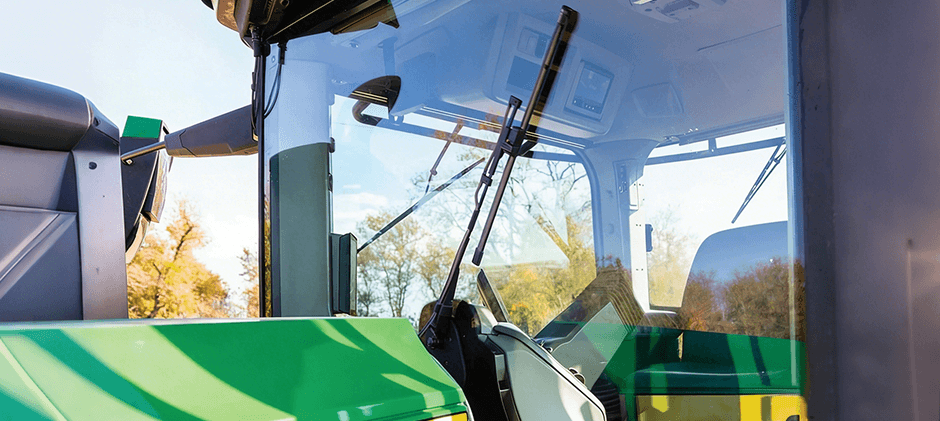 A clear view through the clean windshield of a tractor cab, with the wiper blades resting in the off position.