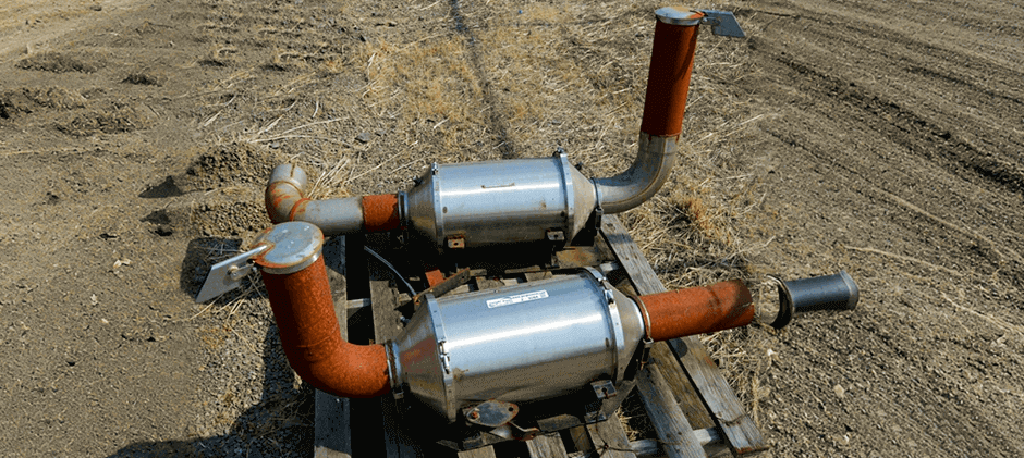 Two complete diesel aftertreatment system units, including the DOC and DPF, removed from heavy equipment and placed on a wooden pallet.