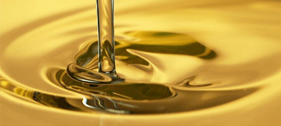 A close-up shot of clean, golden hydraulic fluid being poured, illustrating its viscosity and the importance of fluid quality for cold weather operation.