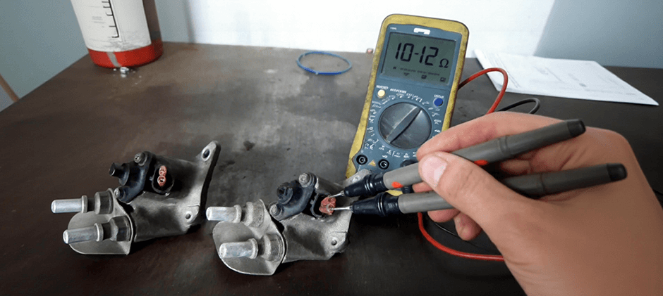 A mechanic is testing the electrical resistance of a DEF dosing valve with a multimeter. The multimeter displays a reading of 10.12 ohms, confirming the part is within the correct specification for a healthy valve.
