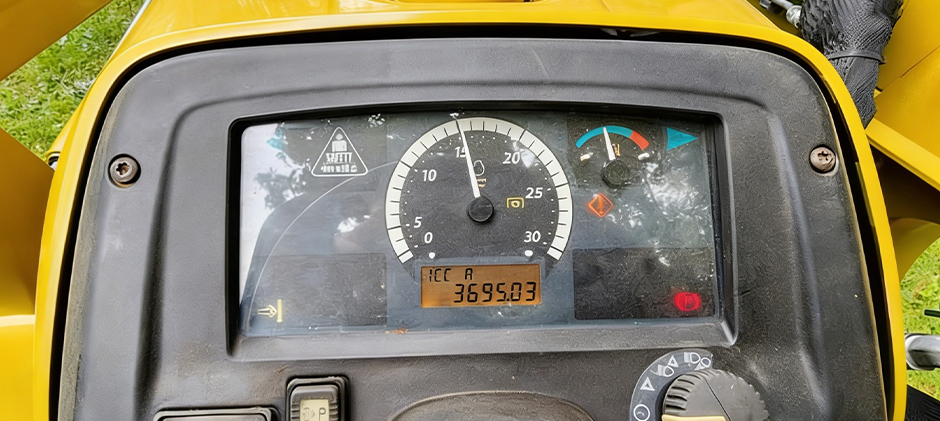 Close-up of a tractor's dashboard showing the instrument cluster with the engine at idle and the low oil pressure warning light illuminated.