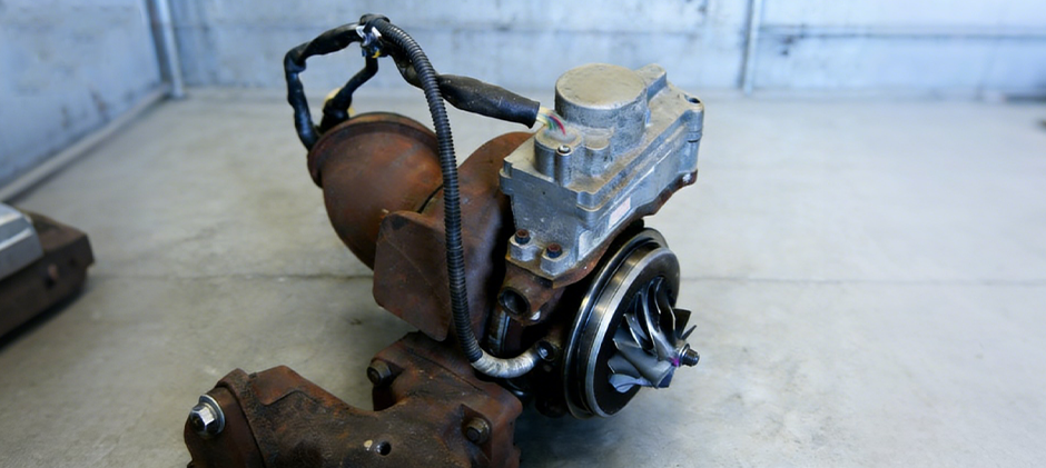 A complete variable geometry turbocharger (VGT) with the electronic actuator motor attached to its side.
