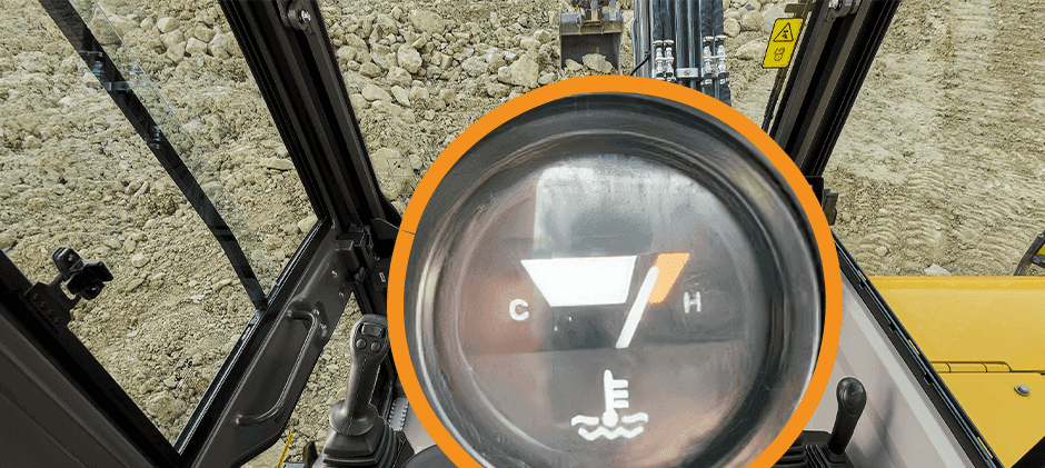 A close-up of a heavy machine's temperature gauge with the needle in the red zone, indicating the engine is overheating.