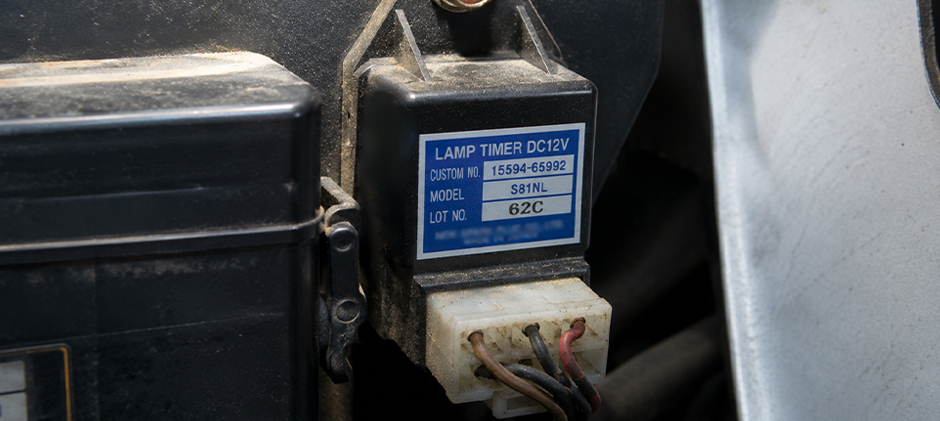 Close-up of a 12V lamp timer relay, showing the part number 15594-65992 and its electrical connector.