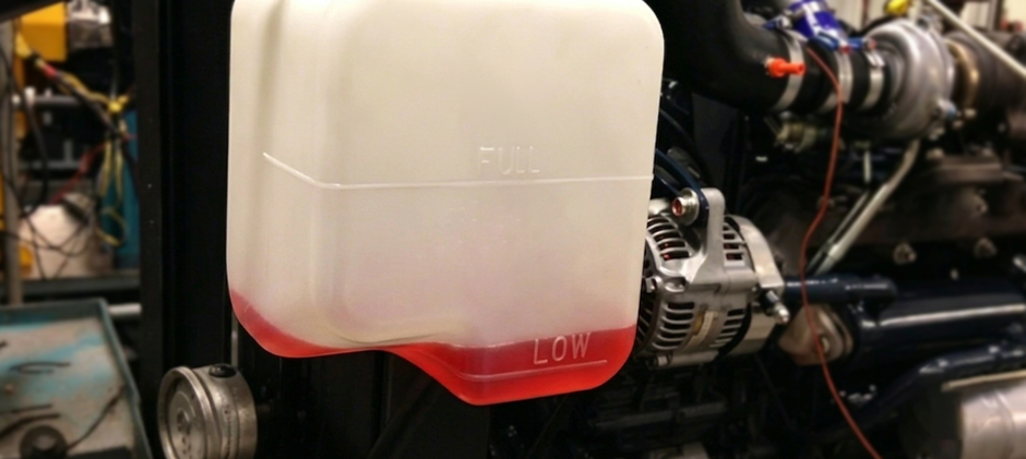 A close-up of a semi-transparent coolant reservoir tank showing the red coolant level below the 'FULL' mark and near the 'LOW' mark.