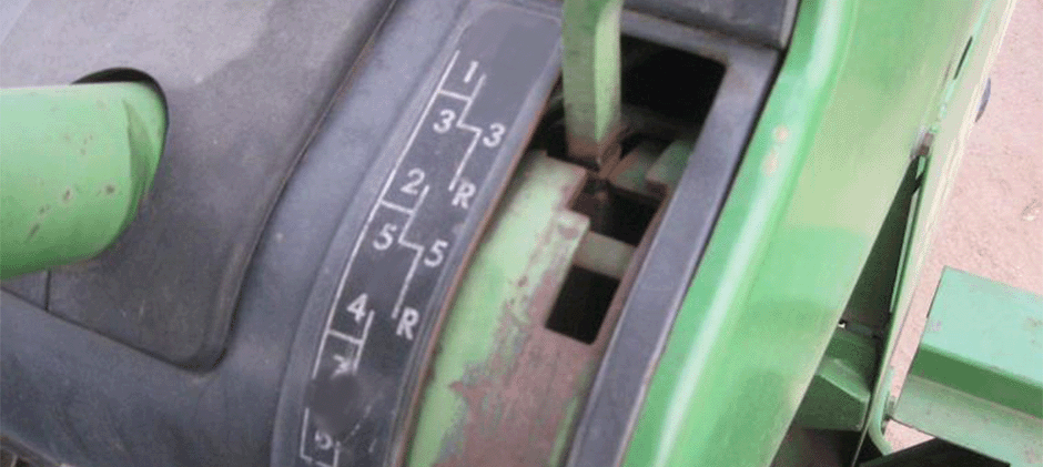 View of a worn gear shift lever on an off-road machine, showing the gear pattern and signs of rust.