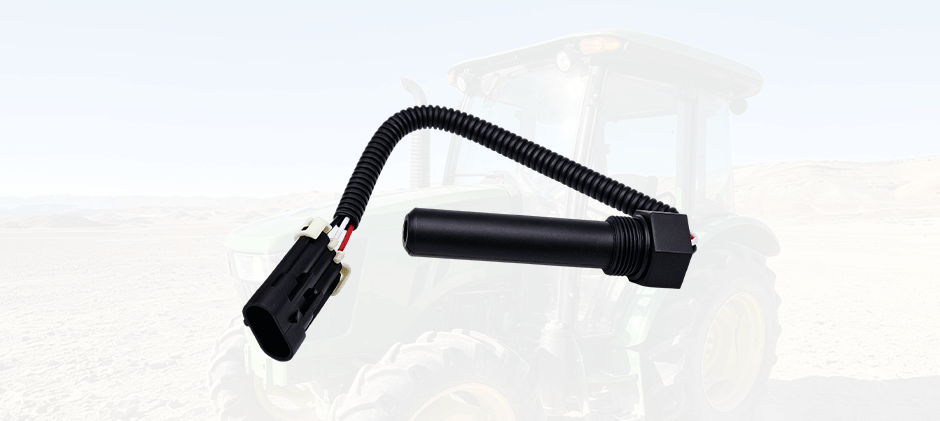 A close-up of a transmission speed sensor with its wiring connector, with a faded image of a tractor in the background.