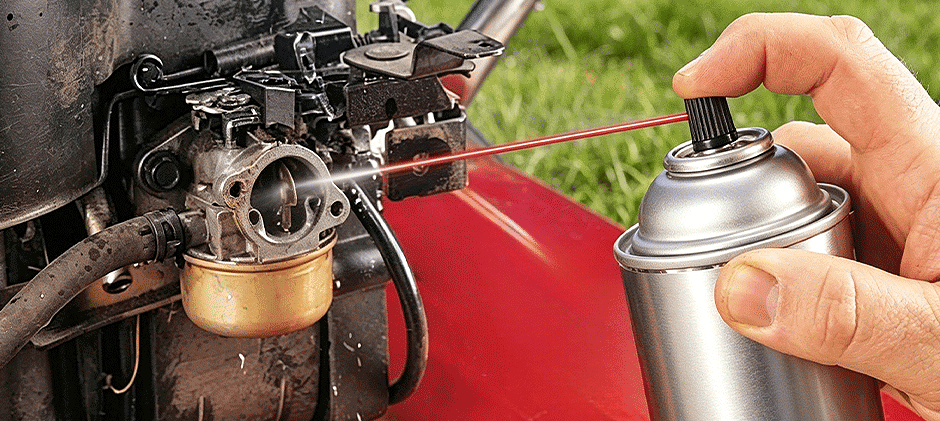 Spraying carburetor cleaner into a lawn mower carburetor without removing it