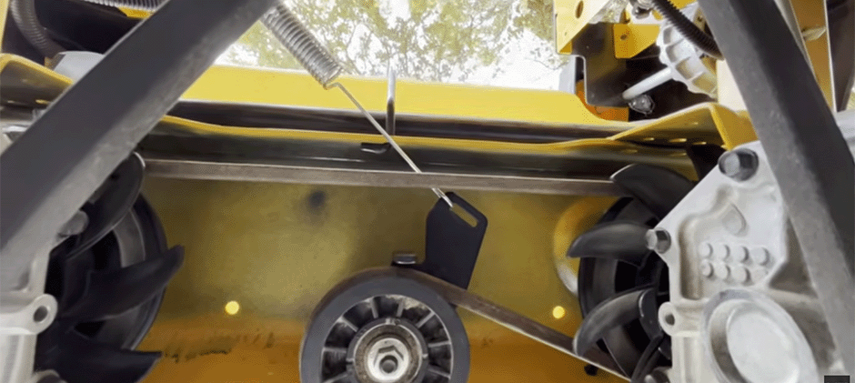 A close-up photo of the drive belt tension spring hook connected to its black mounting bracket on a Cub Cadet mower frame.