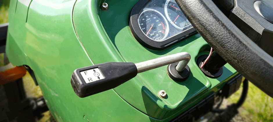 A close-up of a tractor's shuttle shift lever, showing the markings for 'F' (forward) and 'R' (reverse).
