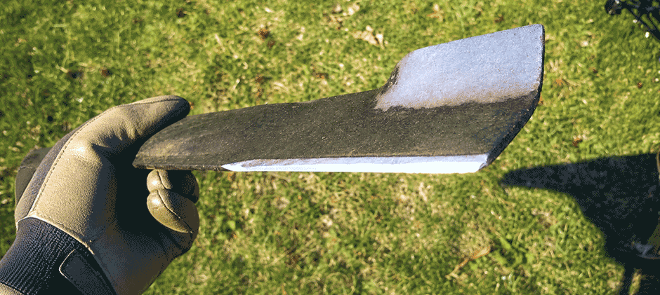 Close-up of a lawn mower blade's sharpened cutting edge and the upward-curved lift wing.