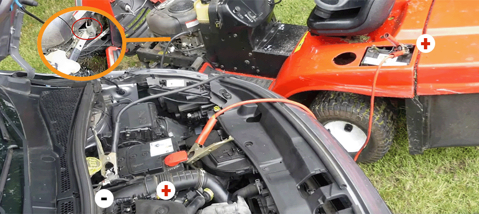 A diagram showing how to connect jumper cables from a car battery to a riding lawn mower battery, including the correct grounding point on the mower's frame.