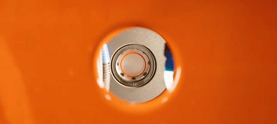 A close-up view of a hydraulic fluid sight glass on a Kubota tractor, showing the correct fluid level with a bubble visible in the center.