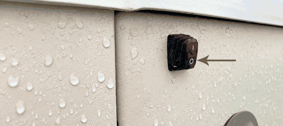 Arrow pointing to the Generac external auxiliary shutdown switch in the off position.