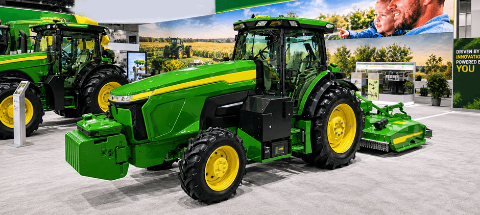 Large John Deere tractor featuring electric drive components at a farm equipment show.