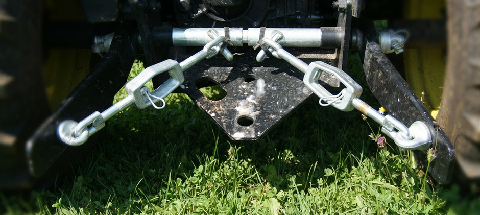 Rear view of tractor lower lift arms with matching turnbuckles on both sides connecting to the hitch.