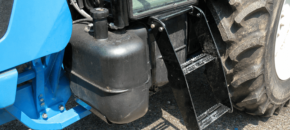 Exterior view of a black diesel fuel tank mounted on a blue tractor.