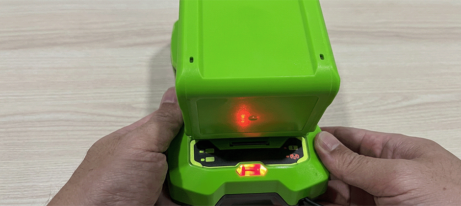 A close-up view of the inside of a Greenworks charger, showing the red diagnostic light that signals a charging error.