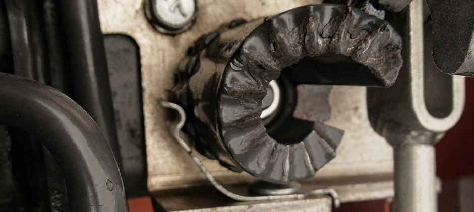 An extreme close-up of a severely worn and damaged height adjustment cam from a mower deck linkage.
