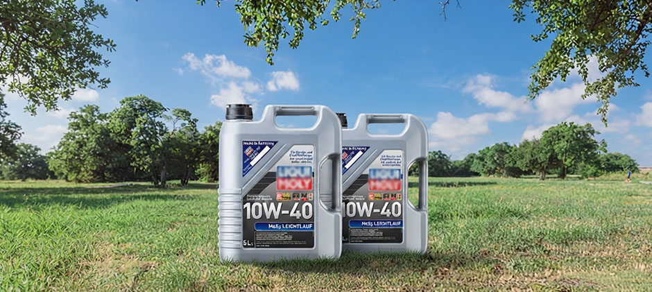 Two jugs of 10W40 engine oil sitting in a grassy field.