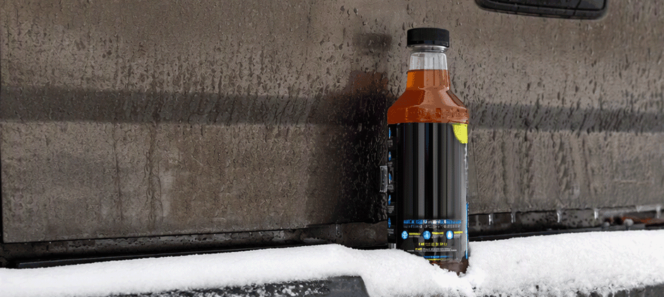 A bottle of diesel fuel treatment sitting on a snow-covered truck bumper.