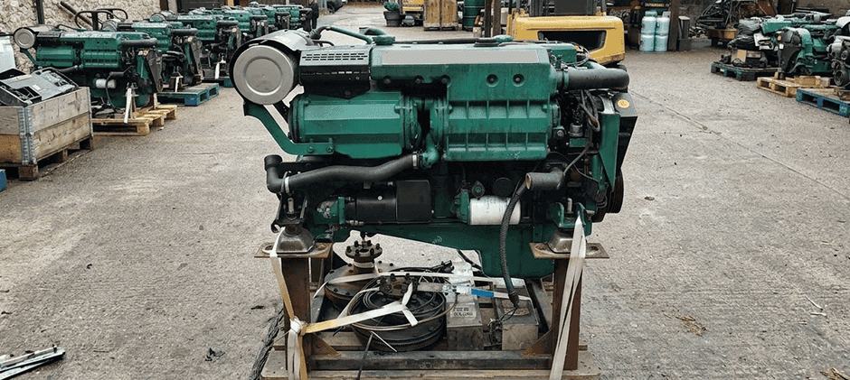 Side view of a green Volvo Penta industrial engine in a workshop or salvage yard.